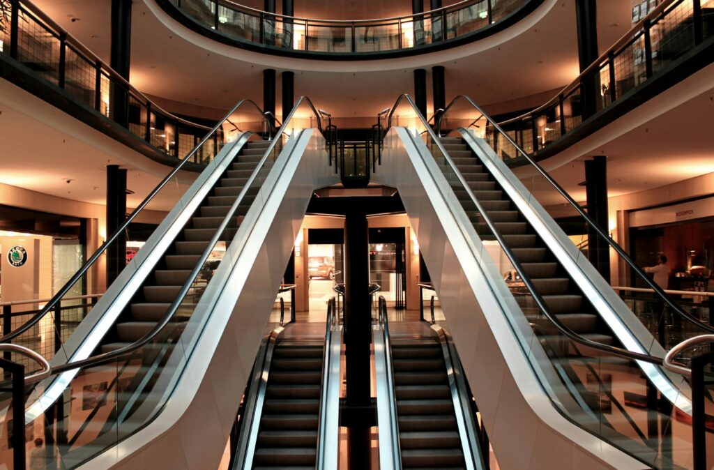Symmetrical view of escalators in a modern shopping mall interior, showcasing architecture and design.